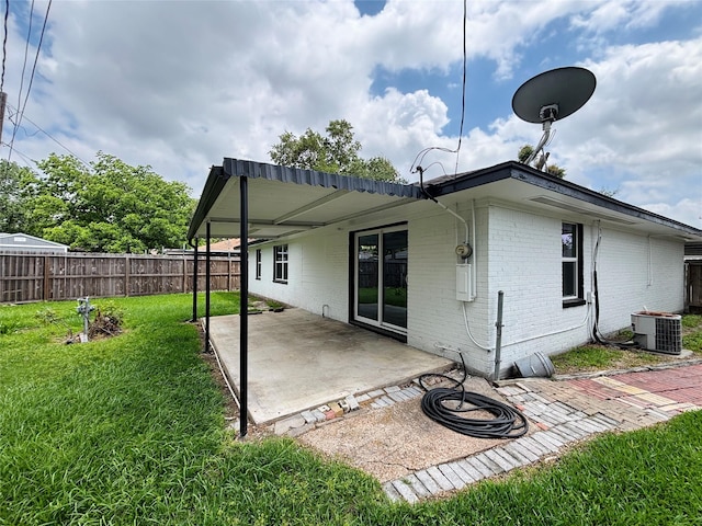 rear view of property featuring fence, brick siding, a patio area, central air condition unit, and a yard
