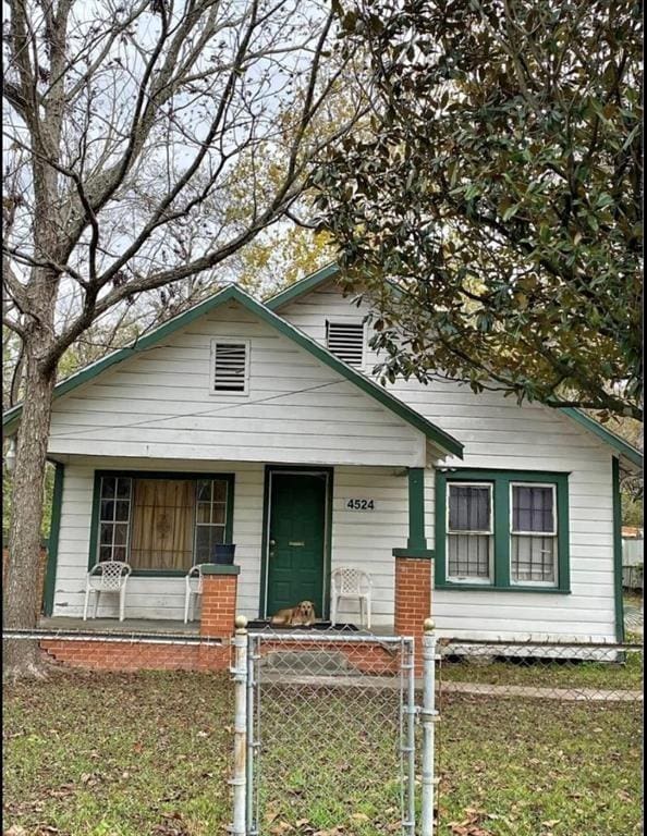 bungalow-style house featuring a porch, a gate, and a fenced front yard