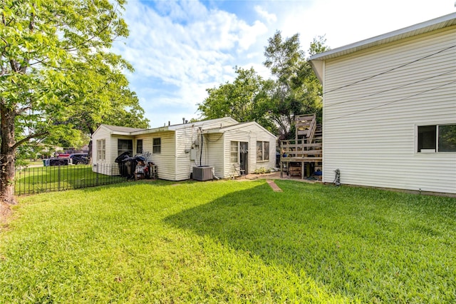 rear view of house with central AC, a yard, a deck, and fence