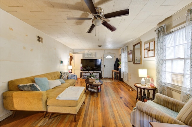 living room with visible vents, ceiling fan, and hardwood / wood-style flooring