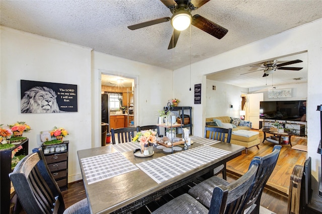 dining room featuring dark wood-style flooring, ceiling fan, ornamental molding, and a textured ceiling