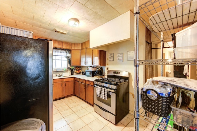 kitchen featuring visible vents, light countertops, brown cabinets, appliances with stainless steel finishes, and light tile patterned floors