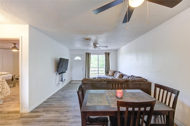 dining space with a ceiling fan, a textured ceiling, visible vents, and light wood-style floors