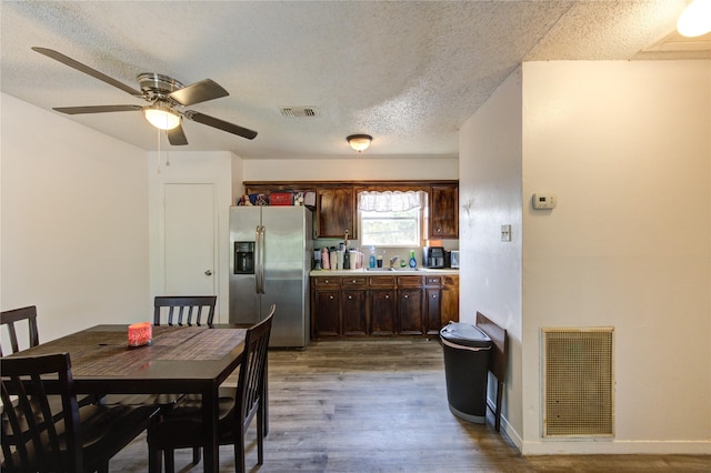 dining room with a textured ceiling, ceiling fan, visible vents, and wood finished floors