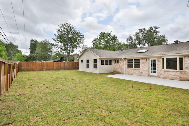 rear view of house with a lawn, a fenced backyard, a patio area, and brick siding