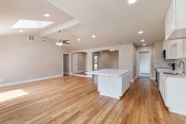 kitchen featuring visible vents, electric range, a kitchen island, stainless steel microwave, and arched walkways