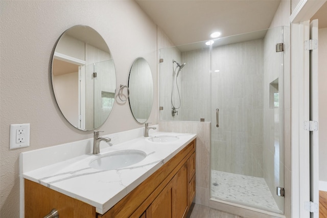 bathroom with double vanity, a sink, and a stall shower