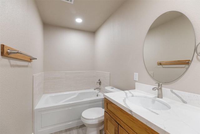 bathroom with a garden tub, wood finished floors, toilet, and vanity