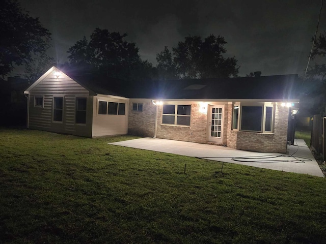12406 Whittington Dr, Houston, TX 77077 - back of house at night featuring a patio, a yard, and brick siding