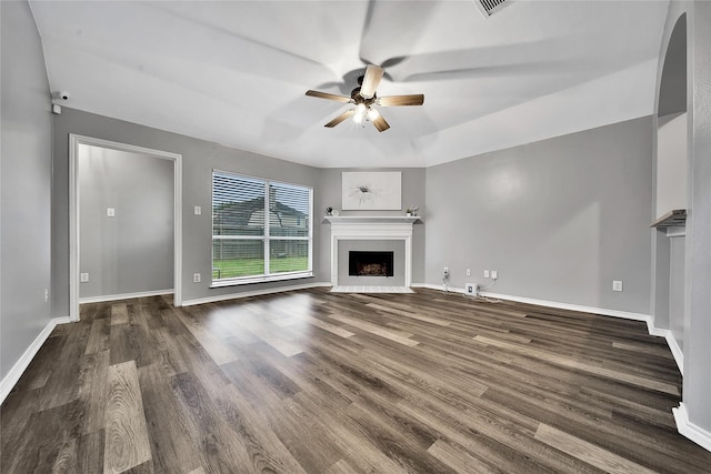 unfurnished living room featuring a ceiling fan, baseboards, a fireplace with flush hearth, wood finished floors, and visible vents