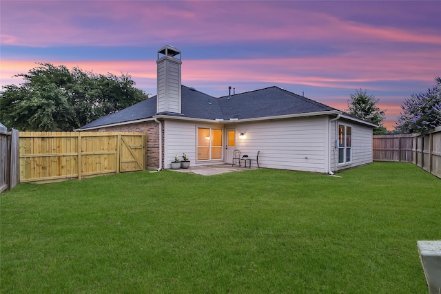 back of house with a fenced backyard, a patio, a chimney, and a lawn