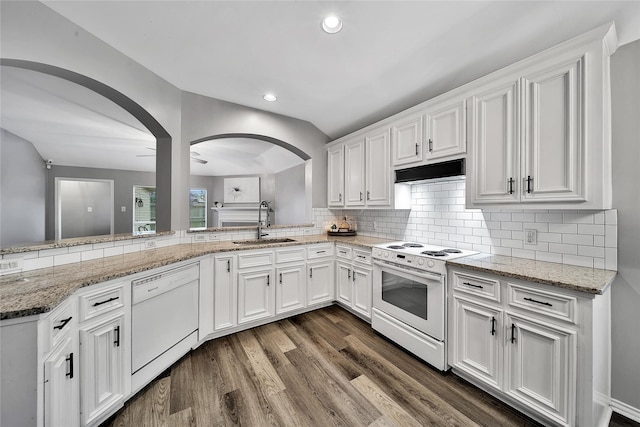 kitchen with white appliances, dark wood-type flooring, arched walkways, under cabinet range hood, and a sink