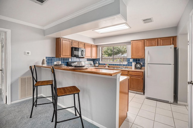 2025 Reef Dr, League City, TX 77573 - kitchen featuring a breakfast bar area, black microwave, tasteful backsplash, a sink, and freestanding refrigerator