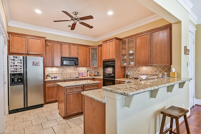 kitchen with a peninsula, brown cabinetry, and black appliances