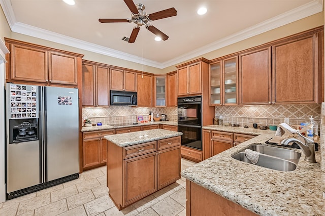 kitchen featuring brown cabinets, light stone countertops, a sink, a kitchen island, and black appliances