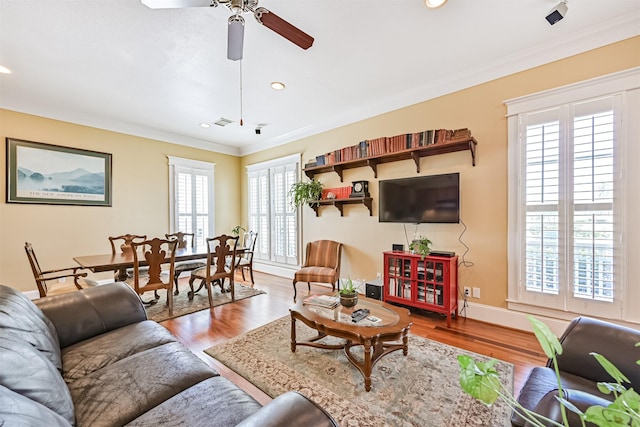 living room featuring a ceiling fan, recessed lighting, ornamental molding, and wood finished floors