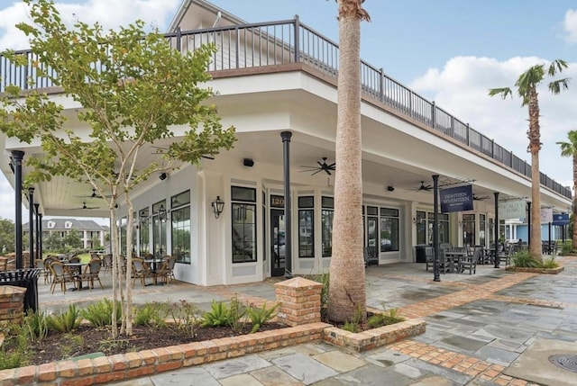 back of property featuring ceiling fan, outdoor dining area, a balcony, and a patio area