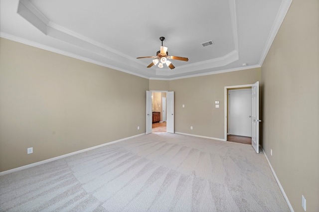 empty room featuring visible vents, crown molding, ceiling fan, light colored carpet, and a tray ceiling