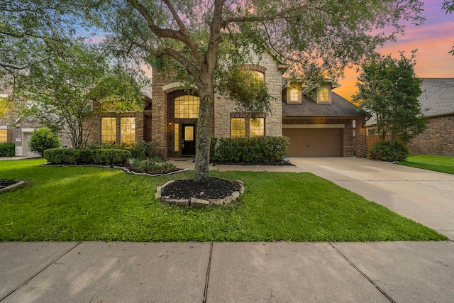 traditional home featuring brick siding, a garage, a front yard, and concrete driveway