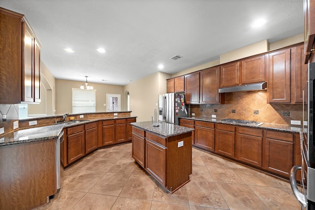 kitchen with appliances with stainless steel finishes, a sink, backsplash, under cabinet range hood, and visible vents