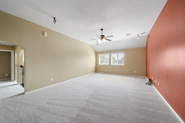 carpeted spare room with visible vents, baseboards, arched walkways, a ceiling fan, and vaulted ceiling