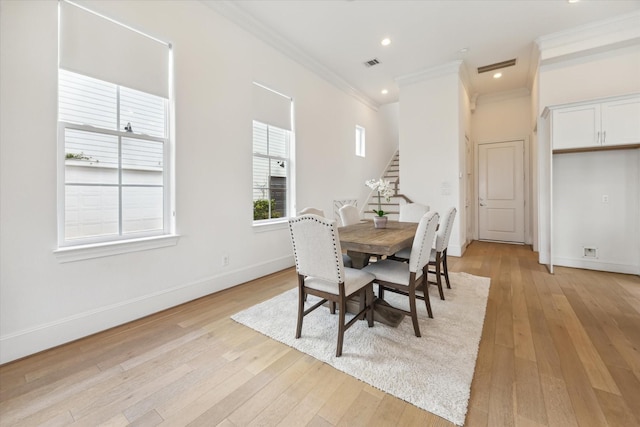 dining area featuring light wood-style floors, ornamental molding, stairs, and visible vents