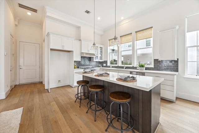kitchen featuring white cabinetry, visible vents, ornamental molding, and a center island