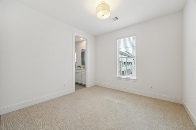 spare room featuring visible vents, baseboards, and light carpet