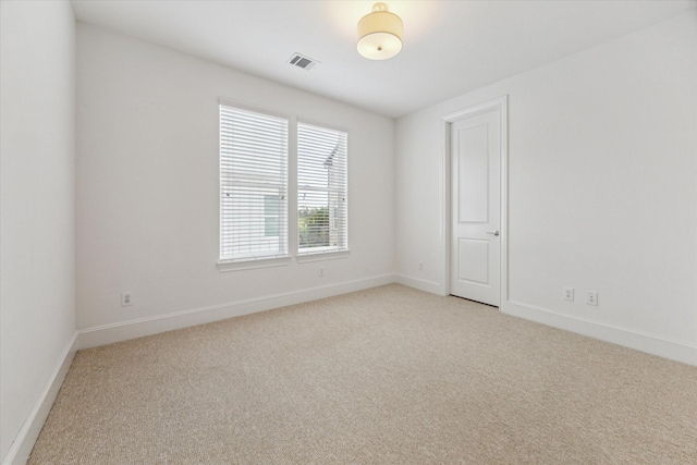 empty room featuring baseboards, visible vents, and light colored carpet