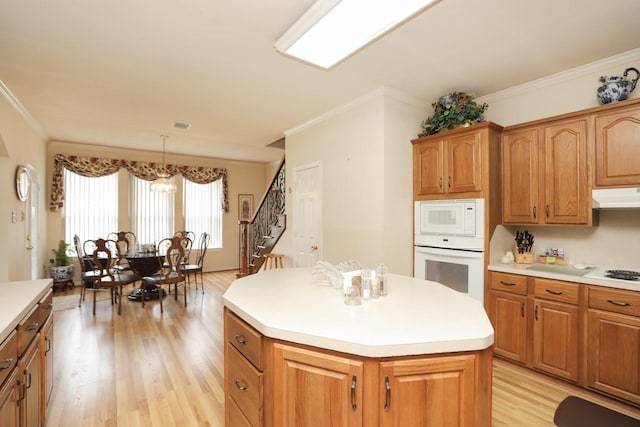 12219 Renaissance Ln, Houston, TX 77071 - kitchen with crown molding, white appliances, light wood-type flooring, a center island, and under cabinet range hood