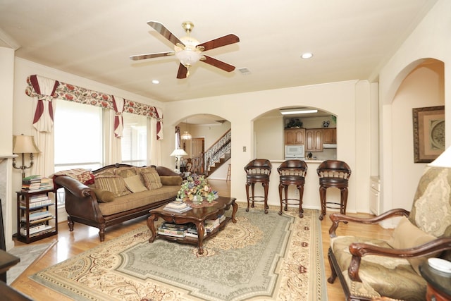 12219 Renaissance Ln, Houston, TX 77071 - living room featuring arched walkways, light wood finished floors, ceiling fan, and ornamental molding