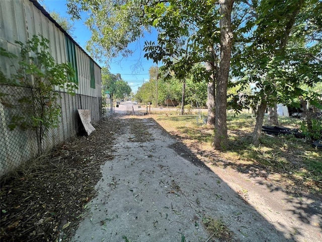 view of yard with dirt driveway and fence