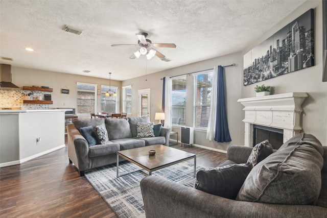 living area featuring visible vents, a textured ceiling, ceiling fan, and dark wood-style floors