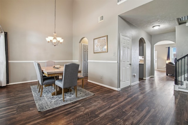 dining room with visible vents, arched walkways, wood finished floors, baseboards, and an inviting chandelier