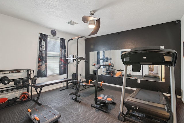 workout room with carpet flooring, ceiling fan, a textured ceiling, baseboards, and visible vents