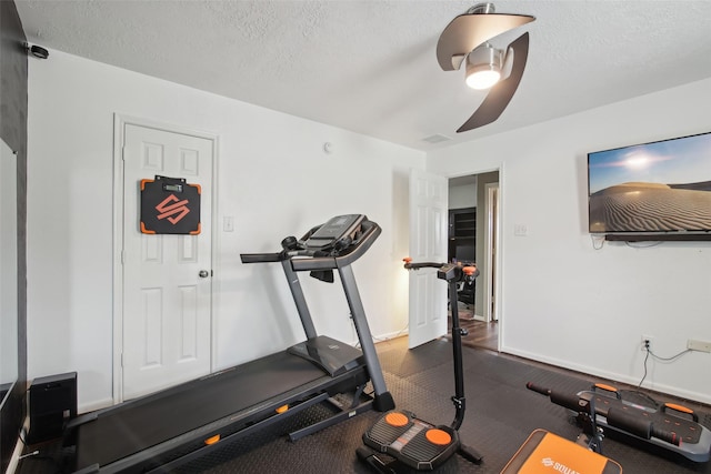 exercise room with a textured ceiling, ceiling fan, and baseboards
