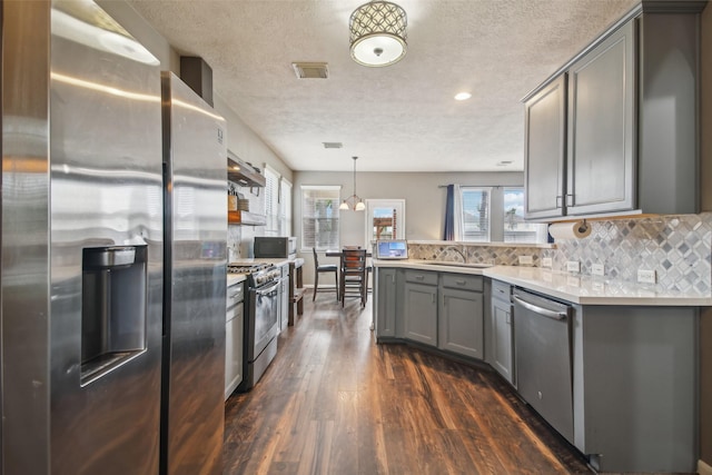 kitchen featuring dark wood-style flooring, ventilation hood, a sink, gray cabinets, and stainless steel appliances