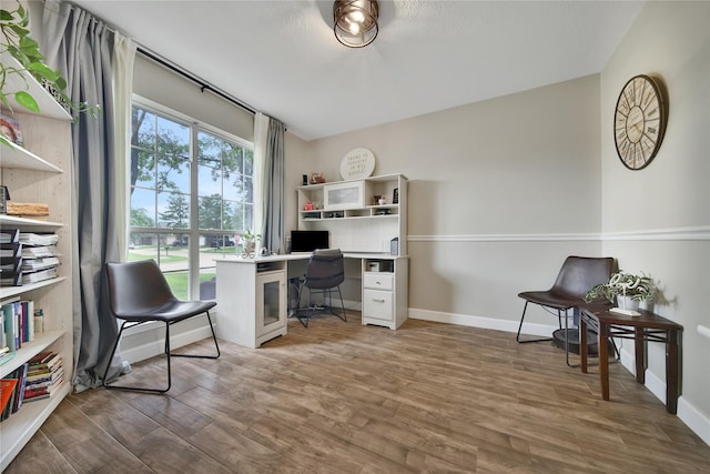home office with baseboards and wood finished floors