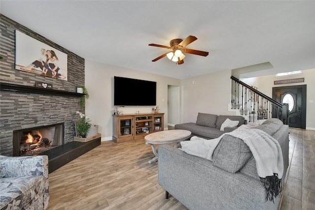 living room with a fireplace, a ceiling fan, stairs, and wood finished floors