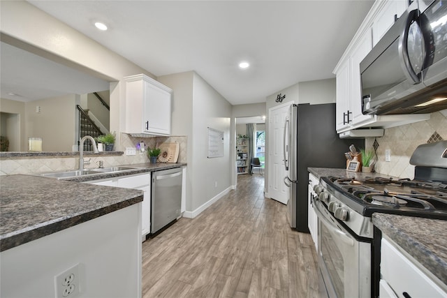 kitchen featuring decorative backsplash, dark countertops, white cabinetry, a sink, and stainless steel appliances