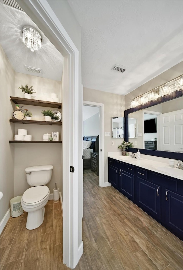 bathroom with a sink, double vanity, wood finished floors, and visible vents