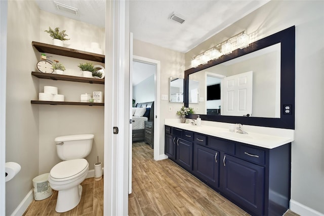 ensuite bathroom featuring a sink, visible vents, wood finished floors, and ensuite bath