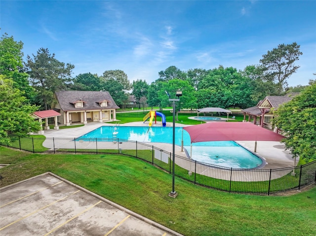pool with fence, playground community, a water play area, a patio, and a yard