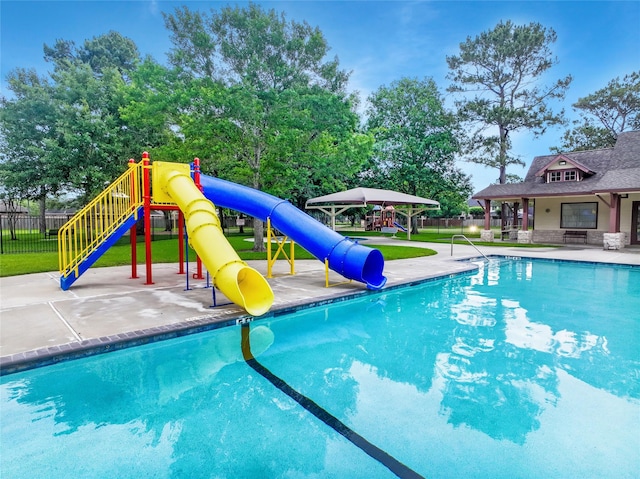 view of pool with playground community, a patio area, fence, a fenced in pool, and a water slide