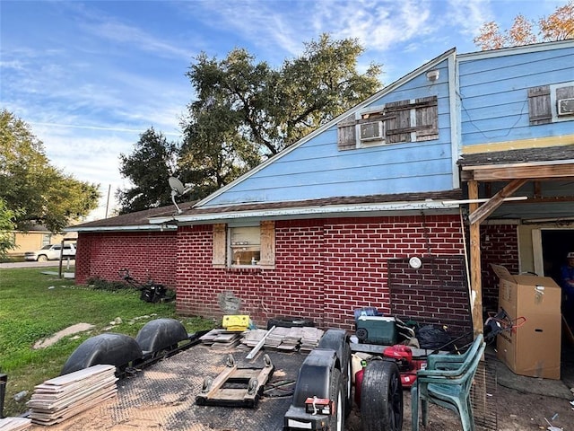 view of side of home with brick siding, a yard, and a patio
