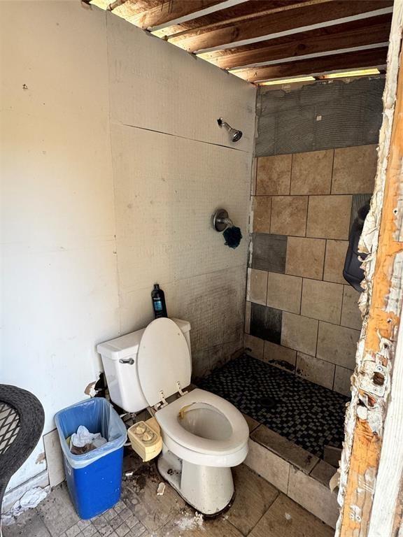 full bathroom featuring toilet and tiled shower