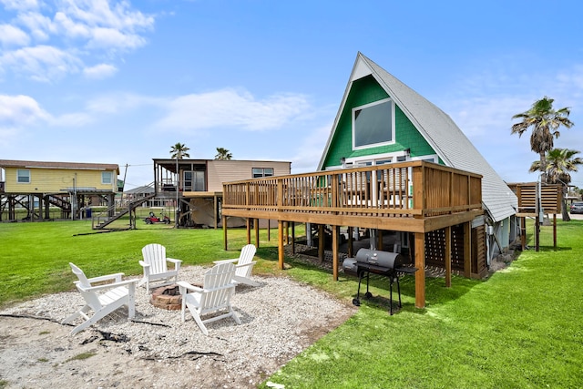 rear view of house with a lawn, a deck, stairs, and an outdoor fire pit
