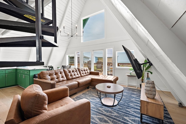 living area featuring an inviting chandelier, light wood finished floors, high vaulted ceiling, and beamed ceiling