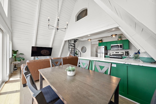 dining space with a notable chandelier, vaulted ceiling with beams, and light wood-type flooring