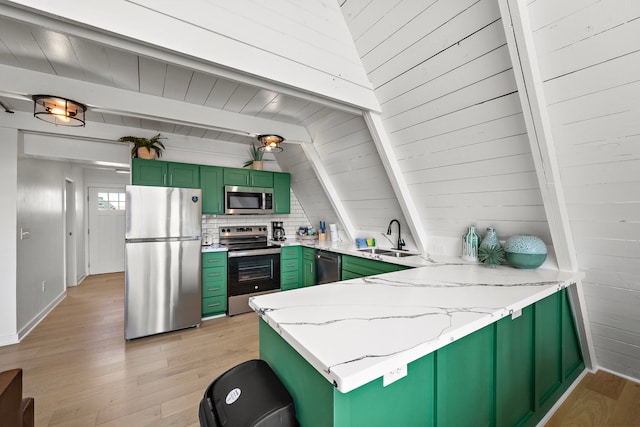 kitchen with appliances with stainless steel finishes, beam ceiling, a sink, a peninsula, and green cabinetry